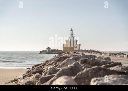 Schönen alten Leuchtturm an der Küste von Venedig Italien Europa. Leuchtturm am Strand mit Felsen und das Meer im Hintergrund Stockfoto