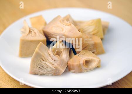 Kleine zarte Stücke von Jackfruit aus Dosen auf dem Teller. Gesunder veganer Fleischersatz und es ist einer der Lebensmitteltrends, da es Fleisch wie Textur ist. Stockfoto