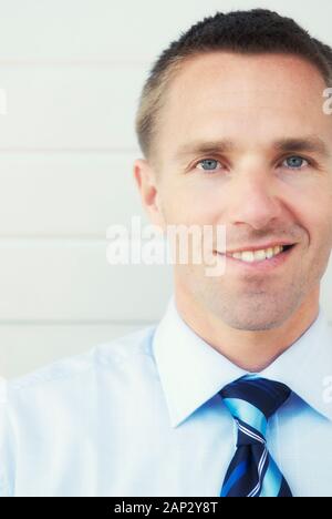 Portrait von Geschäftsmann in blaues Hemd und Krawatte an der Kamera in einem Kopf und Schultern schließen Lächeln - Bis Stockfoto