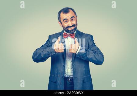 Gerne reife Mitte - bärtiger alter Mann lächelnd geben Daumen bis wie, gute Bewertung mit beiden Händen. Gemischte Rasse bearded Modell isoliert auf Green Yello Stockfoto