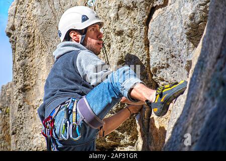 Ein Sportler klettern. Körperliche Aktivität in der Landschaft. Riskante Sportarten. Bergsteigen oder Klettern ist eine gefährliche Übung, dass saf Bedürfnisse Stockfoto