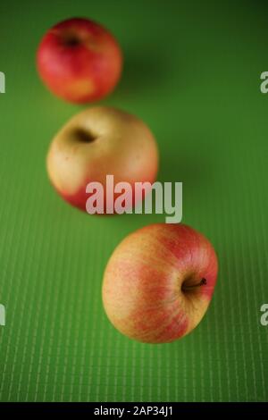 Drei reife Äpfel liegen auf einem grünen Tisch. Stockfoto