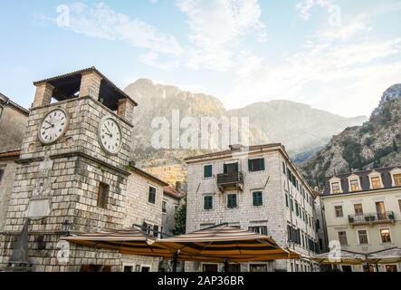 Morgen Sonnenlicht trifft auf die Berge über dem Uhrturm in der Piazza der Arme, die wichtigsten und größten Marktplatz in Kotor, Montenegro Stockfoto