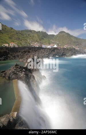 Wilde vulkanische Felsenbecken von Cachalote in Porto Moniz, Madeira, wo mächtige Atlantikwellen gegen dunkle Basaltformationen unter der hellen Küste abstürzen. Stockfoto