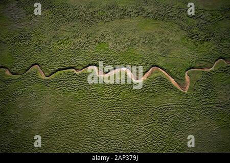 Von oben einen atemberaubenden Luftaufnahmen Landschaft mit grünen Feld und trocken geschwungene Stream in den hellen Tag Stockfoto