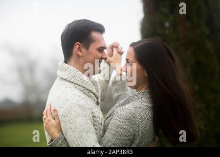 Junges Paar draußen tanzen zusammen in einem Garten Stockfoto