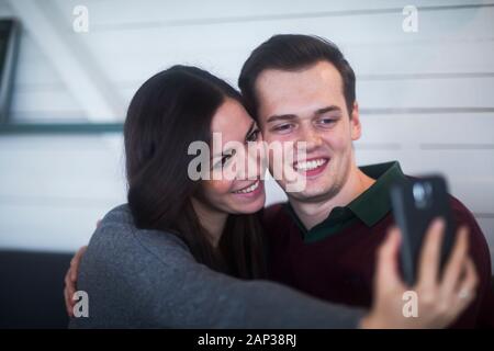 Junges Paar in einem Wohnzimmer in Liebe machen Selfie Stockfoto