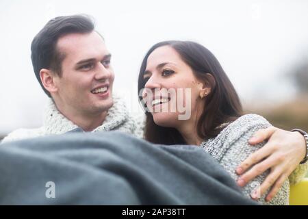 Junges Paar draußen sitzen zusammen in einem Garten Stockfoto