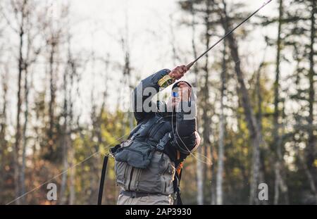 Ein Mann setzt einen Haken beim Fliegenfischen in Maine Stockfoto