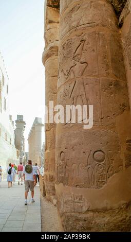 Ägypten, Luxor, Luxor Tempel, معبد الاقصر; Theben. Touristen vorbei Säulen und Wänden mit Schnitzereien und Hieroglyphen bedeckt. Stockfoto