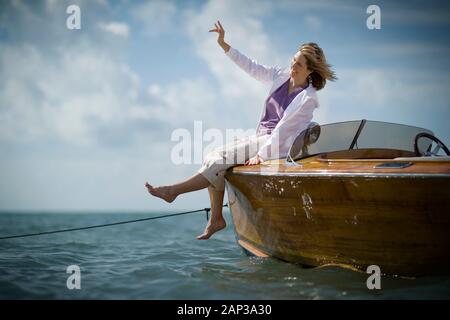 Lachen reife Frau sitzt an der Seite eines Schiffes in den Ozean. Stockfoto