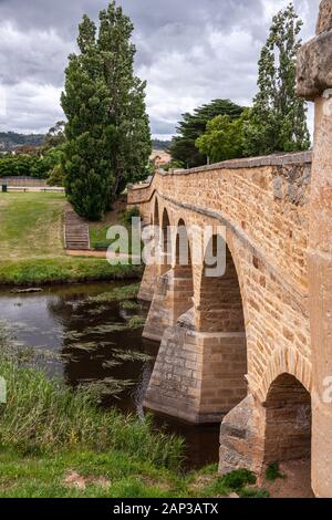 Richmond, Tasmanien, Australien - 13 Dezember, 2009: Porträt entlang der Länge der braun Stein historische Brücke über Coal River unter dunklen cloudscape. Gre Stockfoto