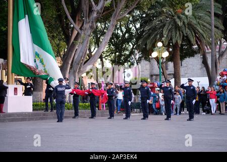 Puebla, Mexiko. Zeremonielle Absenken der Mexikanischen Flagge von der städtischen Polizei in zentralen Platz Stockfoto