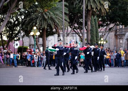 Puebla, Mexiko. Zeremonielle Absenken der Mexikanischen Flagge von der städtischen Polizei in zentralen Platz Stockfoto