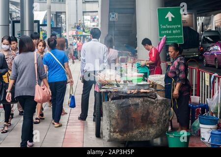 Bangkok, Thailand - 25. September 2012: Pendler, die an Straßennahrungsmitteln vorbeilaufen. Anbieter positionieren sich oft neben Skytrain-Stationen. Stockfoto