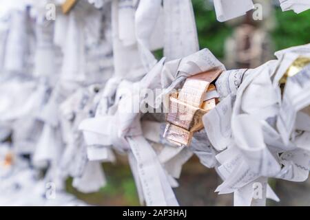 Saga, Japan - November 12, 2018: Japanische random Wahrsagen Papier (OMIKUJI) gefaltet und am Seil Drähte (Omikuji kake) im traditionellen Tempel gebunden, Konze Stockfoto