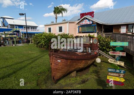 Im Shrimper's Grill and Raw Bar in Port Salerno, Florida, USA, befindet sich ein altes verrostetes Boot auf dem vorderen Rasen. Stockfoto