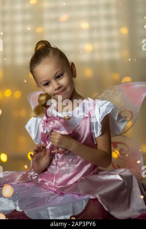 Kleine Fee in ein rosa Kleid mit einer Puppe spielen Stockfoto