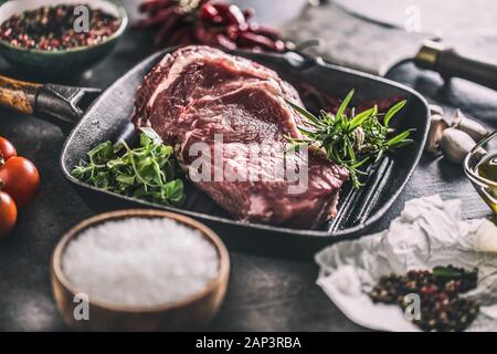 Rindfleisch ribe Eye Steak in der Grillpfanne mit Rosmarin oregano Salz Pfeffer Gewürze Knoblauch und Tomaten Stockfoto