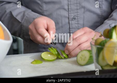 Barkeeper schneidet die Artikel an der Bar draußen, um sie zu den harten Likörgetränken hinzuzufügen Stockfoto