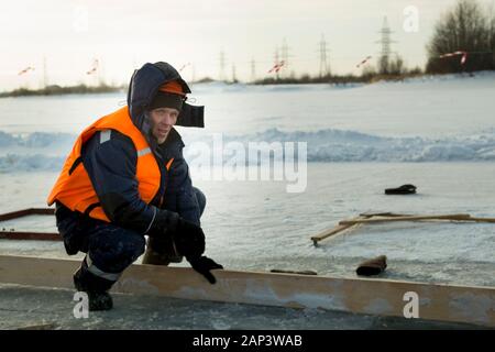 Arbeiter in einem orangefarbenen Helm mit einer Kapuze auf seinem Kopf Stockfoto