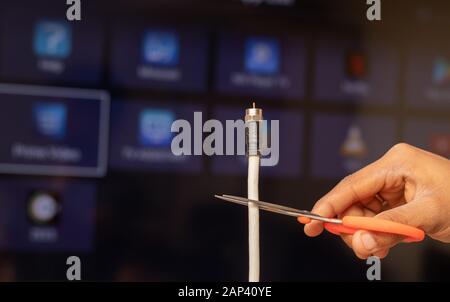 Maski, Indien 18. Januar 2020 - Handschneidende TV-Kabel aus dem Smart TV, die verschiedene Streaming-Dienste im Hintergrund zeigen Stockfoto