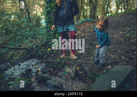 Eine Mutter und ihr kleines Kind rühren ein Bach mit Stöcken Stockfoto