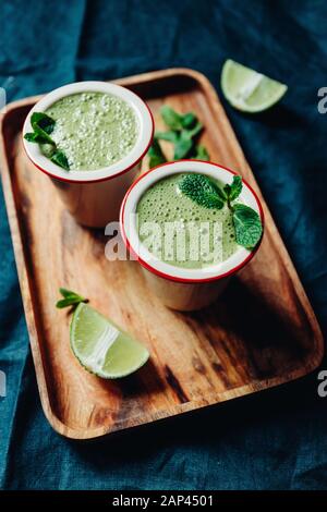 Zwei Portionen grünen Spinat Smoothie mit Banane, Kalk und hafermilch. Stockfoto