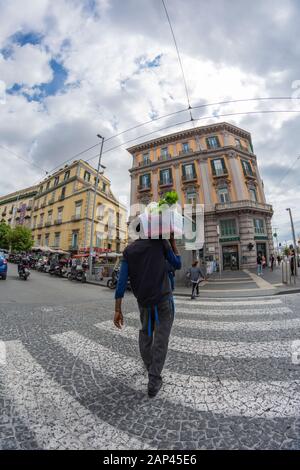 Der Händler bringt Lebensmittel an einen Ort in der Innenstadt von Neapel, der einen Fußgängerweg überquert. Stockfoto