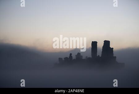 Eine niedrige Nebel umgibt Corfe Castle in Dorset bei Sonnenaufgang, wo über Nacht wieder Temperaturen unter dem Gefrierpunkt getaucht. Stockfoto