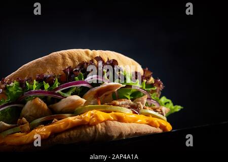 Fladenbrot gefüllt mit Huhn, Salat, Käse Soße und Gemüse auf einem dunklen Hintergrund, selektive konzentrieren. Street Food, Fast Food, dunklen Holzmöbeln backgr Stockfoto