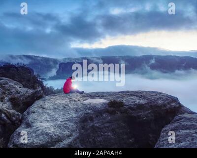 Verlorene Mädchen sitzen auf felsigen Gipfel in darkess Holding in den Händen Symbol der Hoffnung. Kalter Nebel Nacht über der ganzen Welt. Konzepte der Wunder, Untreue, m Stockfoto