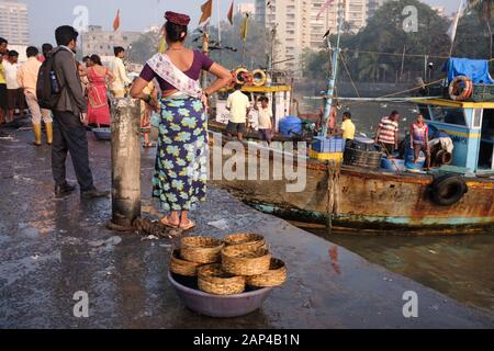 Eine Fischverkäuferin der Koli-Ethnie an den Sassoon Docks, einem Fischerhafen im Colaba-Gebiet, Mumbai, Indien, Fischkörbe im Vordergrund Stockfoto