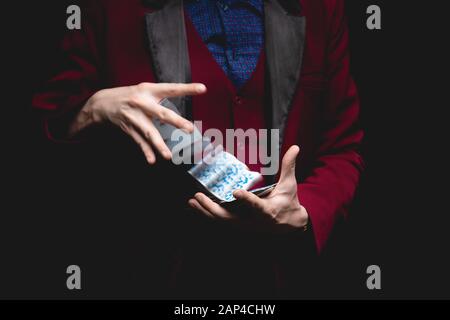 Zauberer zeigt Trick mit Spielkarten auf dunklem Hintergrund, Kopierraum Stockfoto