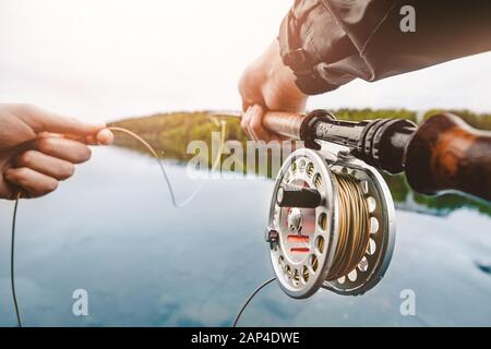 Spule des Fliegenfangseils, Mannhände mit Stab Stockfoto