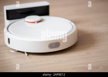 Intelligenter Roboter-Staubsauger mit intelligentem Staubsauger, der auf Laminatboden arbeitet Stockfoto