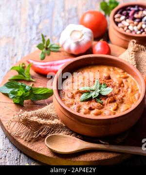 Traditionelle gebackene Bohnen in Tomatensoße in retro Tontopf mit Gewürzen und Gemüse gekocht. Hausgemachte gesunde Küche. Stockfoto