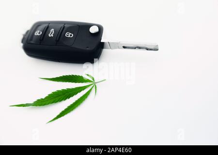 Autoschlüssel mit Cannabisblatt auf weißem Hintergrund, Konzept, das unter Drogen fährt Stockfoto