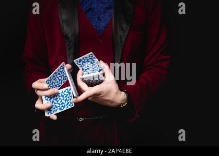 Zauberer zeigt Trick mit Spielkarten, dunklem Hintergrund Stockfoto