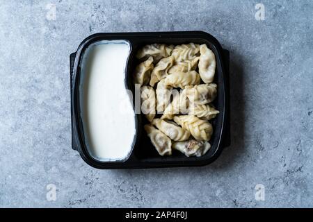 Nehmen Sie den georgischen Knödel Khinkali mit Fleisch, Tomaten, Gewürze und Joghurt in Kunststoff Box Container Paket/Hingel. Bereit zu Essen. Stockfoto