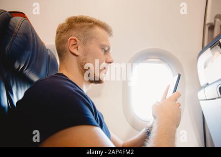 Man verwendet Smartphone im Kabinenflugzeug, Konzept Internet in der Luftstratosphäre Stockfoto