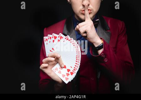 Offenlegung des Fokus. Zauberer zeigt Trick, indem er dieselben Karten auf dunklem Hintergrund spielt Stockfoto
