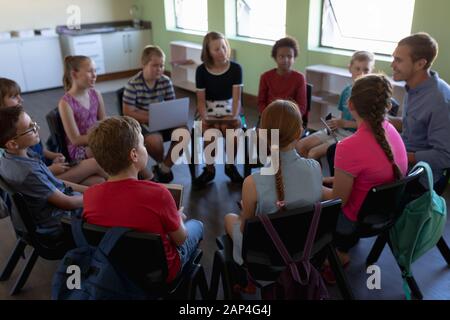 Gruppe von Grundschulkindern, die im Kreis sitzen Stockfoto