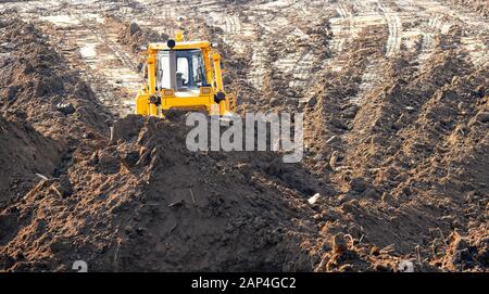 Der Bulldozer entfernt die oberste Schicht fruchtbaren Bodenüberlasts Wald, Gras, Ernteplatz für offene Mine. Konzept Bergbaugeologie Erz Stockfoto