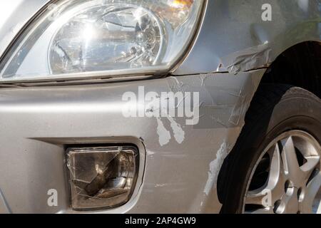 Auto nach einem Crash Unfall auf der Straße, beschädigte vordere Stoßfänger. Klebeband verwendet. Stockfoto