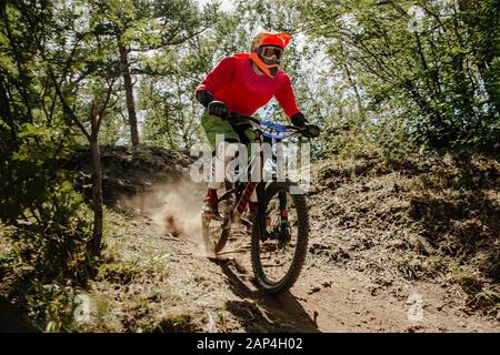 Athlet Rider Downhill Race Dusty Trail im Wald Stockfoto