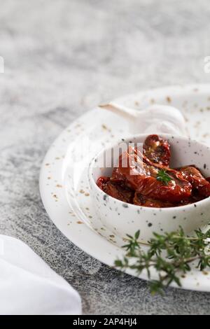 Getrocknete Tomaten in einer Platte auf einem konkreten Hintergrund. Stockfoto
