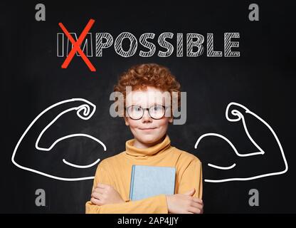 Smart Kid mit Rotkopfhaar und Brille vor Text auf dem Hintergrund des Schwarzen Bretts möglich Stockfoto