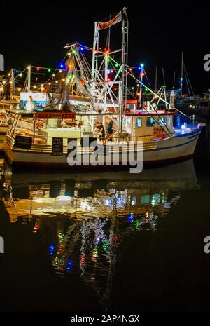 Drawn Star Floating Seafood Restaurant Trawler Boat, frische Meeresfrüchte in der Nacht mit bunten Reflexionen, Cairns Marina, Queensland, Australien Stockfoto