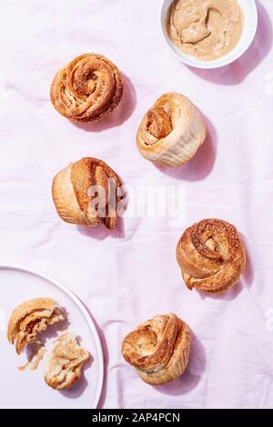 Moderne, trendige GebäckCruffins (Croissant und Muffin) mit Zimt, braunem Zucker und veganer cremiger Nuss-Cashew-Butter auf pinkfarbenem Textilhintergrund Stockfoto